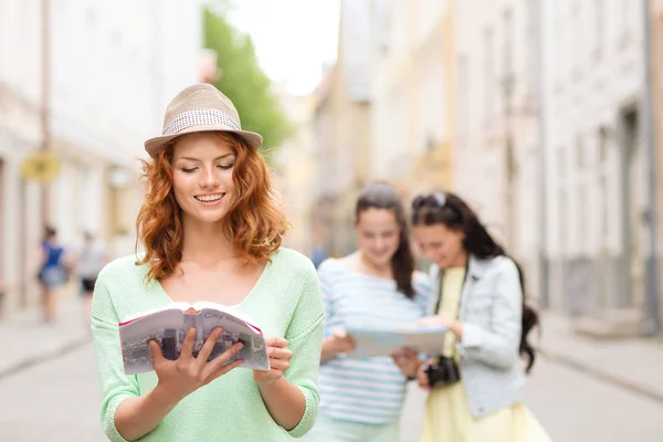 Smiling teenage girls with city guides and camera — Stock Photo, Image