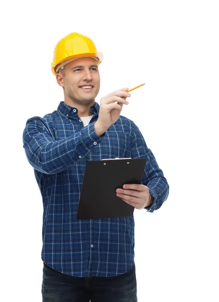 Constructeur masculin souriant dans le casque avec presse-papiers Photo De Stock