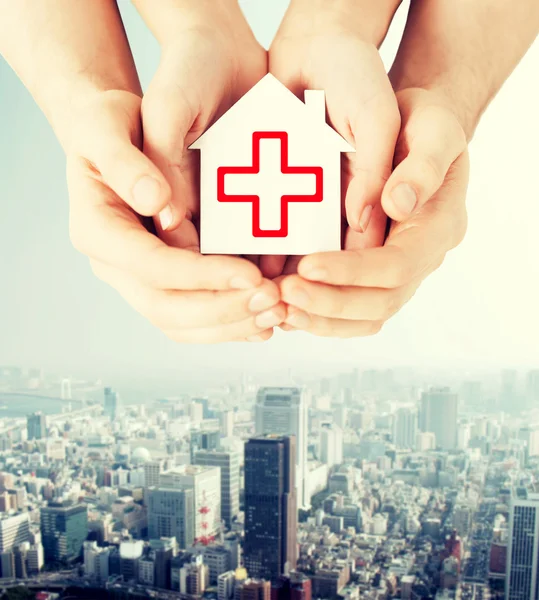Hands holding paper house with red cross — Stock Photo, Image
