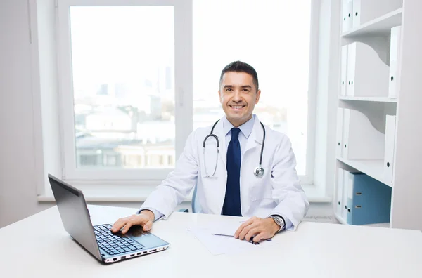 Sorridente médico masculino com laptop em consultório médico — Fotografia de Stock