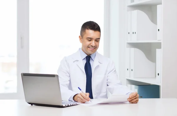 Sorridente médico masculino com laptop em consultório médico — Fotografia de Stock