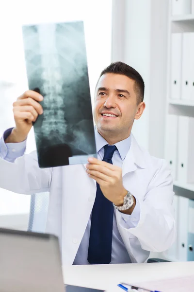 Sorridente médico masculino em casaco branco olhando para raio-x — Fotografia de Stock