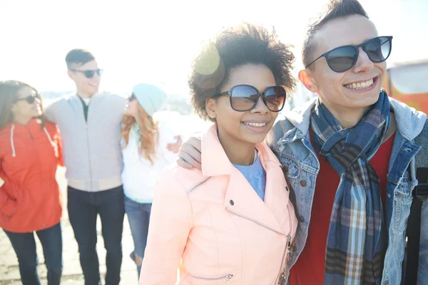 Happy teenage friends in shades hugging on street — Stock Photo, Image