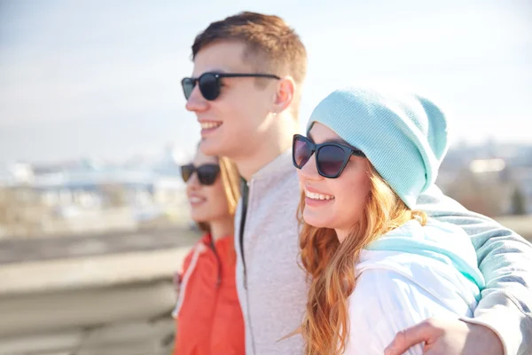 Happy teenage friends in shades hugging on street — Stock Photo, Image