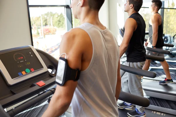 Lächelnde Männer beim Training auf dem Laufband im Fitnessstudio — Stockfoto