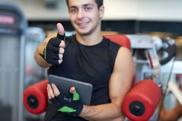 Hombre joven con tablet pc mostrando los pulgares hacia arriba en el gimnasio —  Fotos de Stock