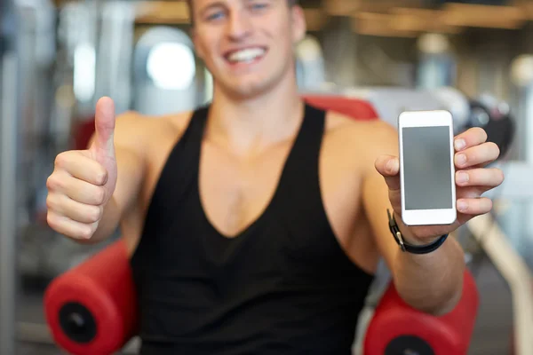 Giovane con smartphone mostrando i pollici in palestra — Foto Stock