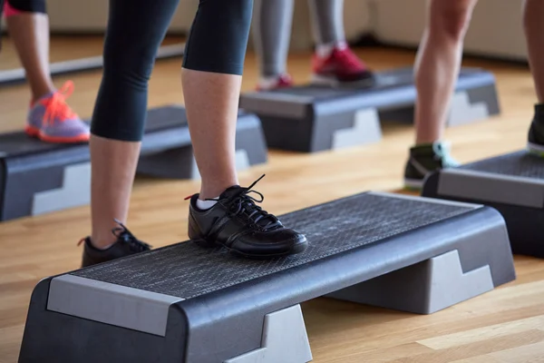 Primer plano de las mujeres haciendo ejercicio con los pasos en el gimnasio — Foto de Stock