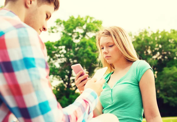 Couple with smartphones in park — Stock Photo, Image