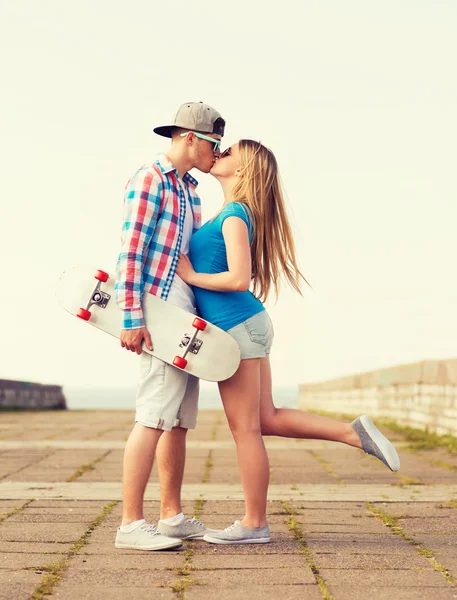 Glimlachend paar met skateboard zoenen buitenshuis — Stockfoto