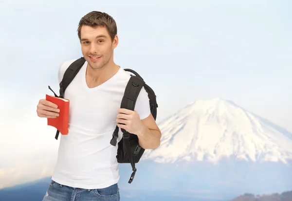 Щасливий молодий чоловік з рюкзаком і книга подорожує — стокове фото