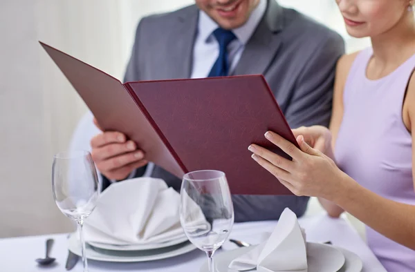 Close up of happy couple with menu at restaurant — Stock Photo, Image