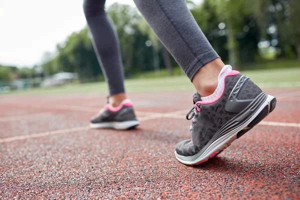 Primer plano de los pies de la mujer corriendo por la pista desde atrás — Foto de Stock