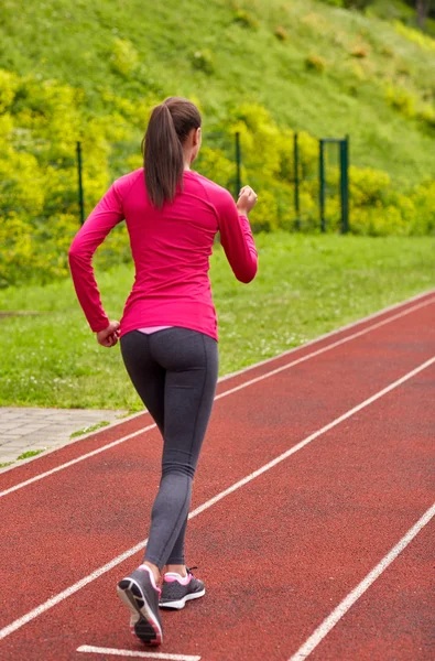 Femme courir sur la piste à l'extérieur de dos — Photo