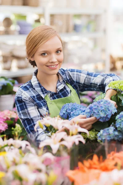 Glückliche Frau kümmert sich um Blumen im Gewächshaus — Stockfoto