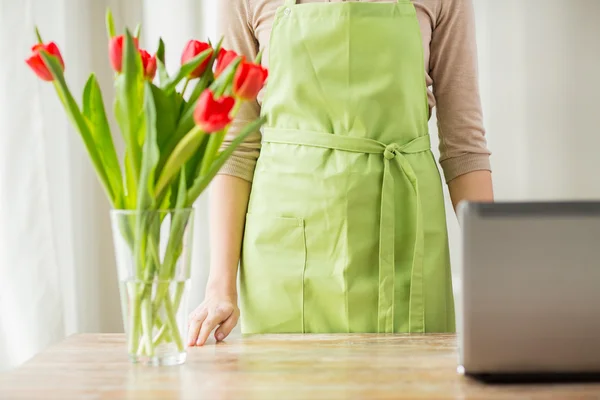 Närbild på kvinna med tulpaner i vas och laptop — Stockfoto
