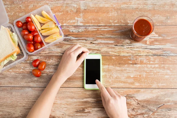 Primer plano de las manos con comida para teléfonos inteligentes en la mesa — Foto de Stock