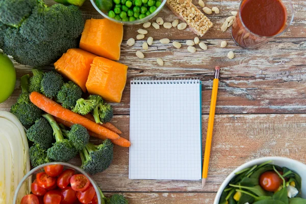 Close up of ripe vegetables and notebook on table — Stock Photo, Image