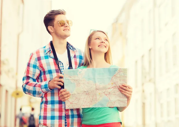 Coppia sorridente con mappa e macchina fotografica in città — Foto Stock