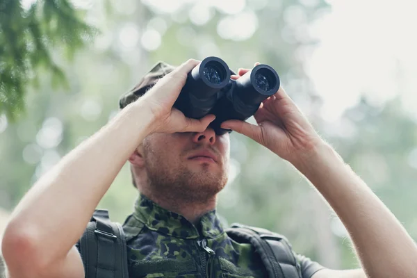 Young soldier or hunter with binocular in forest — Stock Photo, Image