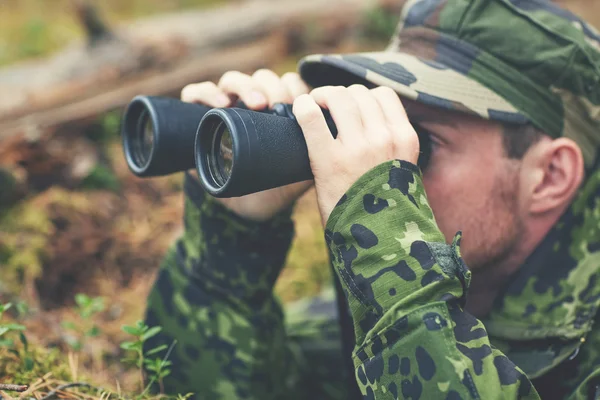 Young soldier or hunter with binocular in forest — Stock Photo, Image