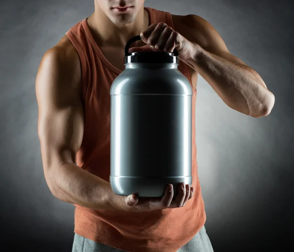 Jovem fisiculturista masculino segurando frasco com proteína — Fotografia de Stock