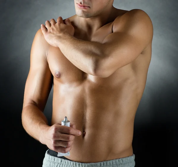 Молодой культурист-мужчина применяет гель для снятия боли — стоковое фото