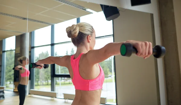 Frau mit Kurzhanteln lässt Muskeln im Fitnessstudio spielen — Stockfoto