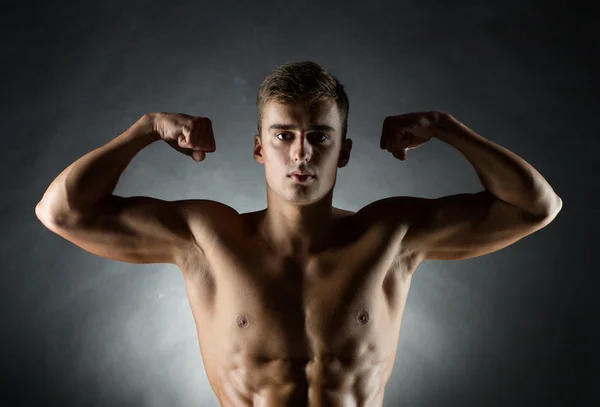Mladý muž zobrazeno biceps — Stock fotografie