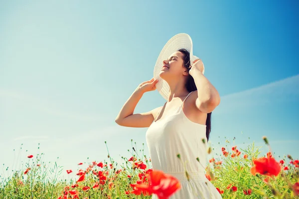 微笑在草帽上罂粟花田里的年轻女子 — 图库照片