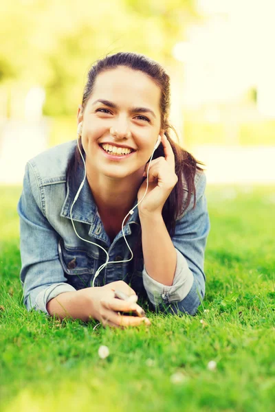 Akıllı telefon ve kulaklık ile gülümseyen genç kız — Stok fotoğraf