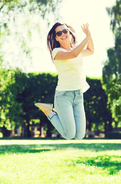 Jeune femme souriante avec des lunettes de soleil dans le parc — Photo