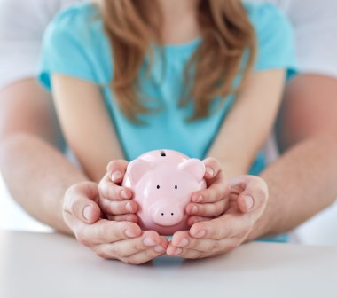 close up of family hands with piggy bank clipart