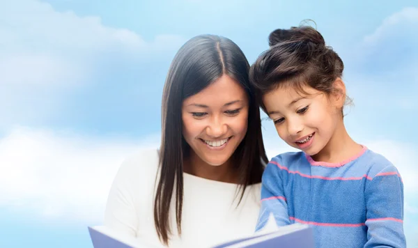 Счастливая мать и дочь читают книгу — стоковое фото