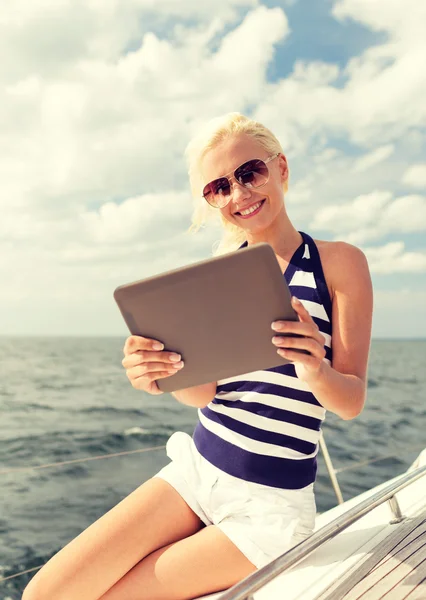 Усміхнена жінка сидить на яхті з планшетним ПК — стокове фото