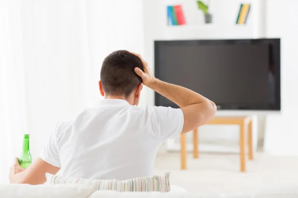Человек смотрит телевизор и пьет пиво дома — стоковое фото
