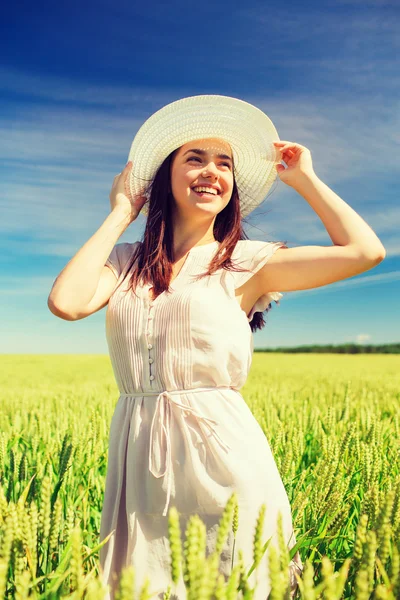 Lächelnde junge Frau mit Strohhut auf einem Getreidefeld — Stockfoto