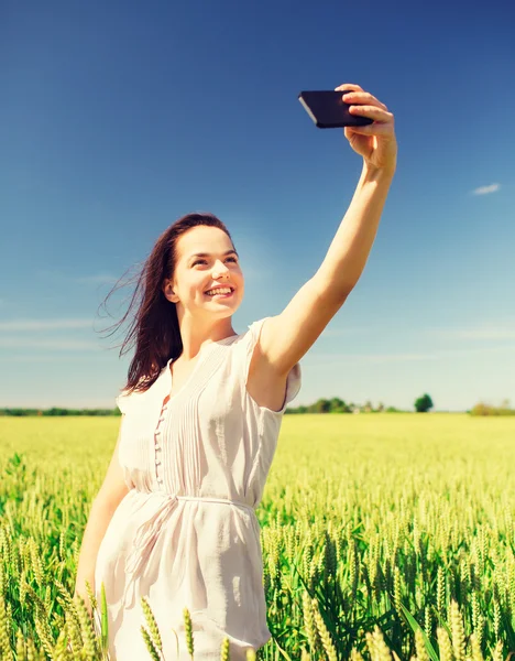 Ragazza sorridente con smartphone sul campo di cereali — Foto Stock