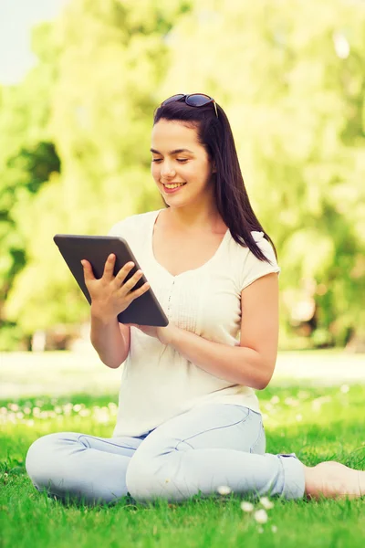 Leende ung flicka med TabletPC sitter på gräset — Stockfoto