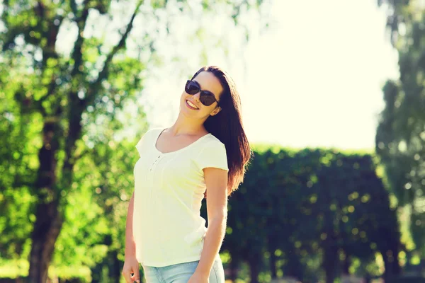 Sorrindo jovem mulher com óculos de sol no parque — Fotografia de Stock