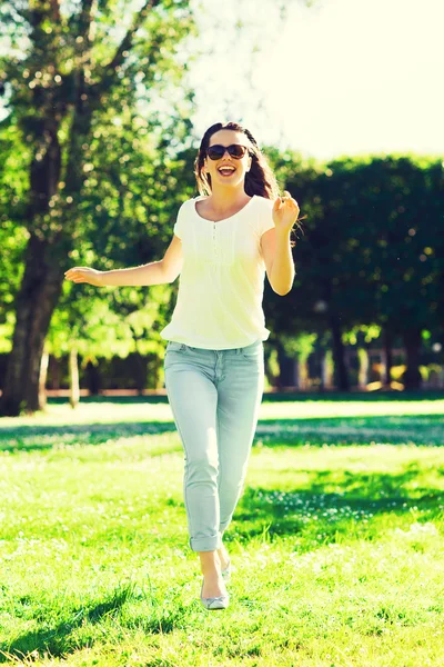 Lachende jonge vrouw met zonnebril in park — Stockfoto