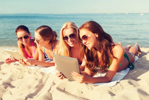 Groep van jonge vrouwen met tabletten op strand glimlachen — Stockfoto