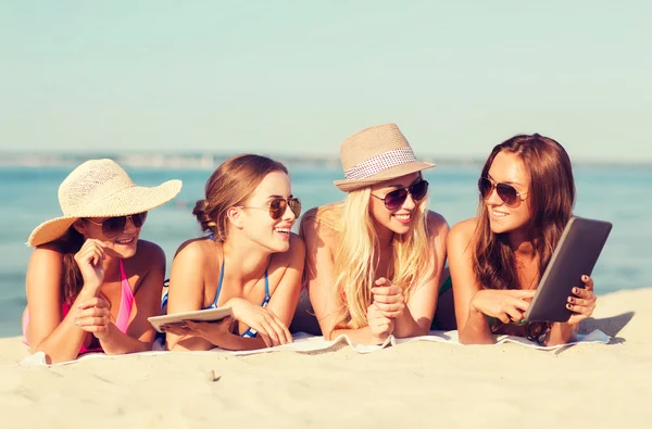 Группа улыбающихся молодых женщин с таблетками на пляже — стоковое фото