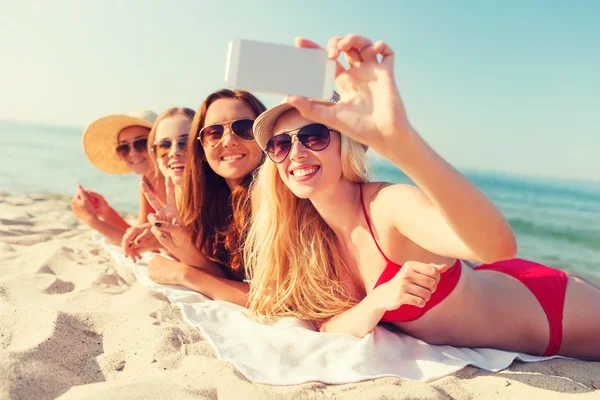 Groep van de lachende vrouw met smartphone op strand — Stockfoto