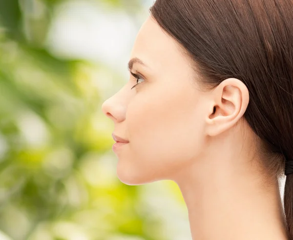 Mooie jonge vrouw gezicht op groene achtergrond — Stockfoto