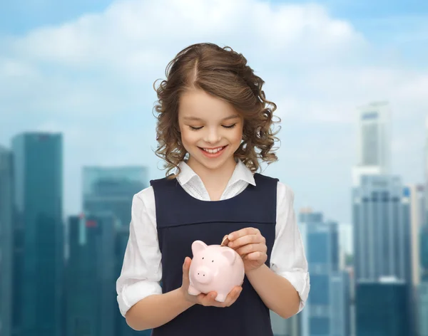 Menina feliz colocando moeda no banco porquinho — Fotografia de Stock