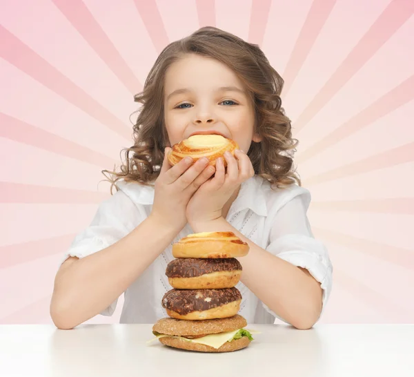 Happy little girl eating junk food — Stock Photo, Image