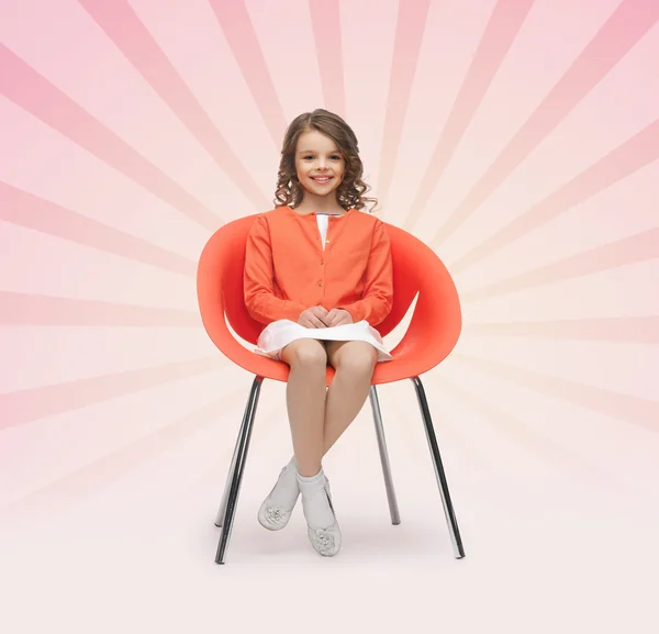 Счастливая маленькая девочка, сидящая на дизайнерском стуле — стоковое фото
