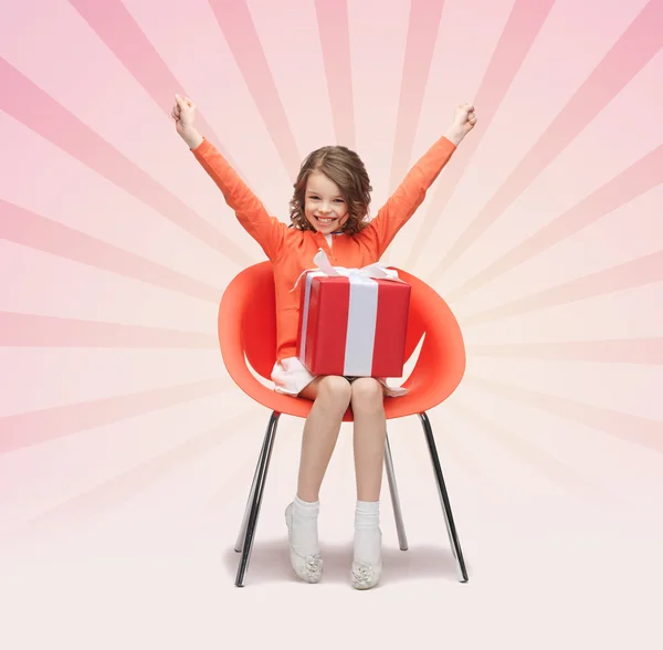 Happy little girl with gift boxes sitting on chair — Stock Photo, Image