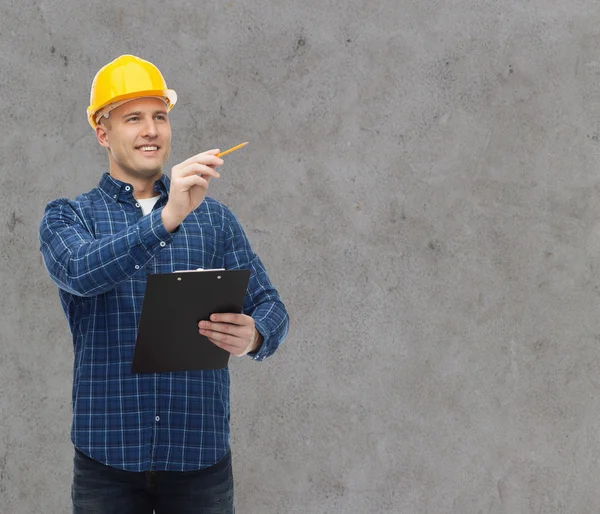 Улыбающийся мужчина-строитель в шлеме с планшетом — стоковое фото